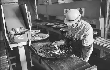  ??  ?? Isamu Kamiya paints a manhole cover at a factory in Otawara, Tochigi prefecture.