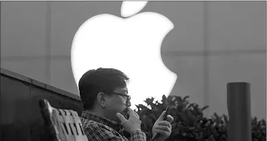  ?? Associated Press ?? A man uses his mobile phone near an Apple store on May 13 in Beijing. Apple reported financial results on Tuesday.
