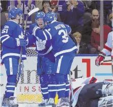  ?? AP PHOTO ?? RISING AND FALLING: Josh Leivo (center) celebrates his goal with Maple Leafs teammates during last night’s 4-2 victory against goalie Keith Kinkaid and the Devils.
