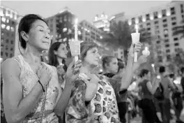  ?? RICARDO RAMIREZ BUXEDA/ORLANDO SENTINEL ?? Sam Jitaree, left, and Devi Thompson, of Orlando, hold candles at a vigil in 2016 for the victims of the shooting at Pulse nightclub that left 49 dead and more than 50 wounded.