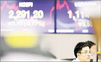 ?? (AP) ?? A currency trader watches the computer monitors near the screens showing the Korea Composite Stock Price Index (KOSPI) (left), and the foreign exchange rate between US dollar and South Korean won at the foreign exchange dealing room in Seoul, South...