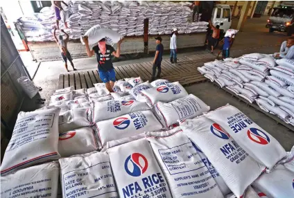  ?? SUNSTAR FILE ?? CHEAPER VARIETY. Workers transfer some 200,000 sacks of rice to a National Food Authority (NFA) warehouse in Cebu City in June. Aside from assuring enough stock for the region, the NFA 7 also said it has not received complaints about pests in the rice.