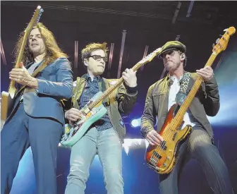  ?? STAFF PHOTOS BY CHRIS CHRISTO ?? KINGS OF THE WORLD: Members of Weezer, from left, Brian Bell, Rivers Cuomo and Scott Shriner, perform at Boston Calling last night. Cuomo, below, plays guitar.