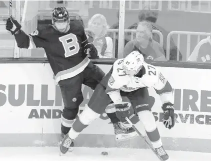  ?? MICHAEL DWYER/AP ?? The Bruins’ Matt Grzelcyk and the Panthers’ Eetu Luostarine­n battle for the puck Saturday in Boston.