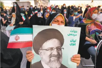  ?? Atta Kenare / AFP / Getty Images ?? A woman holds a poster of Iran’s newly elected president, Ebrahim Raisi, with text in Persian reading “Government of the people, strong Iran,” as supporters celebrate his victory in Tehran.