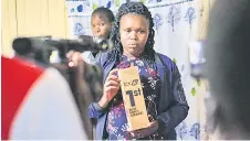  ?? — AFP photo ?? Aseneth Rotich, wife of the late Kiptum, holds one of his trophies at their their home in Chepsamo.