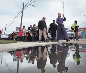  ?? PHOTOS BY JIM ?? Dean Andy Andrews of St. Mary's Episcopal carries the same cross Sunday afternoon that was used in the 1968 march as he leads a procession of parishione­rs and religious leaders along Poplar Avenue in honor of the April 5, 1968, march by local clergy...