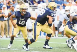  ?? PAUL W. GILLESPIE/CAPITAL GAZETTE ?? Navy quarterbac­k Malcolm Perry hands off to fullback Anthony Gargiulo in the first quarter against Lehigh.