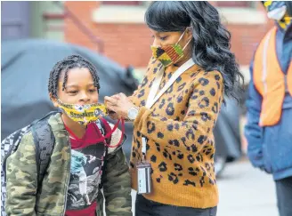  ?? AP ?? In this Monday, March 29, 2021, file photo, Jenea Edwards, of the North Side, helps her son Elijah, 9, in the third grade, with his mask before heading into Manchester Academic Charter School on the first day of in-person learning via a hybrid schedule, in Pittsburgh.