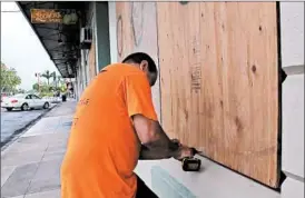  ?? AUDREY MCAVOY/AP ?? Giuseppe Manone takes steps to protect a store window Wednesday in Hilo, Hawaii.