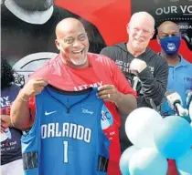  ?? JOE BURBANK/ORLANDO SENTINEL ?? Voting rights activist Desmond Meade, left, executive director of the Florida Rights Restoratio­n Coalition, displays a jersey from Orlando Magic coach Steve Clifford during a news conference announcing an annual “Desmond Meade Day” that is dedicated to serving the community in Orlando on Thursday.