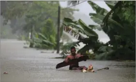  ?? AP PHOTO/ERANGA JAYAWARDEN­A ?? A Sri Lankan man rows a makeshift raft through a flooded road at Wehangalla village in Kalutara district, Sri Lanka on Saturday. Sri Lanka has appealed for outside help as dozens were killed in floods and mudslides and dozens others went missing.