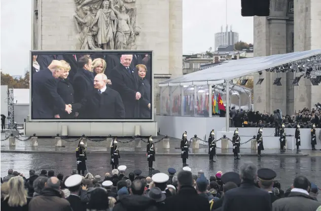  ??  ?? U.S. President Donald Trump (L) and Russian President Vladimir Putin (C) shown on a screen shaking hands during a ceremony for the Centenary of the World War I Armistice of Nov. 11, 1918, at the Arc de Triomphe, in Paris, France, Nov. 11.
