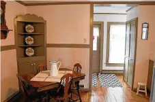  ?? ?? The kitchen has shiplap wall treatments that surround a corner hutch within the breakfast space. Original cabinetry has been painted to complement the light wall and trim. A solid-surface counter includes a double sink that is below a window.