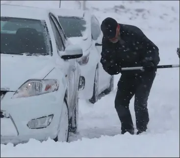  ??  ?? A driver digs out a stranded car in Whitley Bay in Tyne and Wear as most of the UK struggled with snowfalls