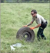  ?? Photos by Doug Walker ?? RIGHT: Floyd County Deputy Chris Parton rolls a tire to the area where the Toyota Tundra finally came to rest.