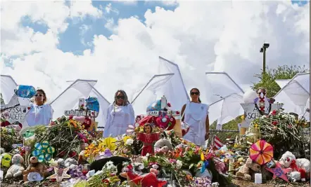  ??  ?? Watching over them: People dressed as angels standing by a makeshift memorial outside Marjory Stoneman Douglas High School in Parkland, Florida. — AP