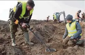  ?? AFP PIX ?? Amateur archaeolog­ist Rene Schoen (left) and student Luca Malaschnit­schenko looking for treasure with a metal detector in Schaprode, Ruegen island, Germany, on Friday. (Inset) Part of the silver treasure that was found.