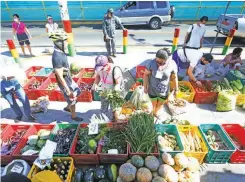  ??  ?? Market-goers buy goods from vendors at a Kadiwa Market in Punta, Sta. Ana in Manila (Ali Vicoy)