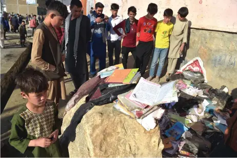  ?? — AFP ?? Onlookers stand next to the backpacks and books of victims following multiple blasts outside a girls’ school in Dasht-e-Barchi on the outskirts of Kabul. photos