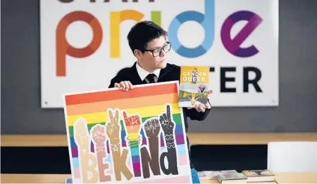  ?? RICK BOWMER/AP ?? Amanda Darrow, director of youth and family programs at the Utah Pride Center, poses with books that have been the subject of complaints.