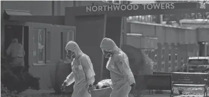  ?? TIM KROCHAK/SALTWIRE NETWORK ?? Workers in full personal protective equipment (PPE) are seen removing a waste bin from a residence in the Northwood Center in Halifax.