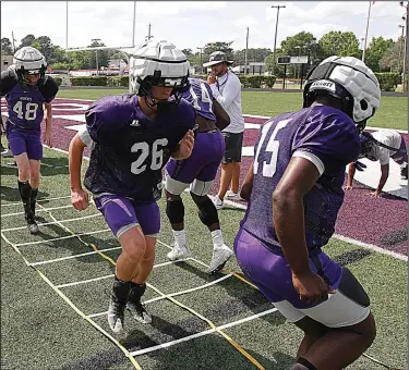  ?? Terrance Armstard/News-Times ?? Guardian Caps: El Dorado's football players run through drills while wearing Guardian Caps over their helmets. The caps are designed to reduce impact and head-related injuries.