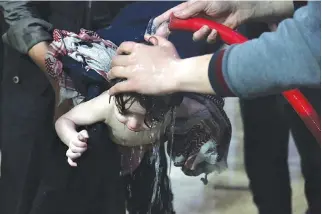  ??  ?? AN APR. 7 photo shows emergency response staff washing chemicals off a baby in a hospital in Douma, eastern Ghouta in Syria, after what a Syria medical relief group claims was a suspected chemical attack.