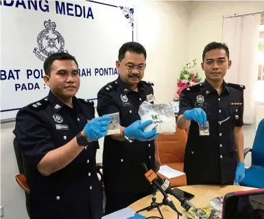  ??  ?? Definitely not Chinese tea: supt mustafa (centre) along with other officers holding the drugs confiscate­d during a raid in Pontian.