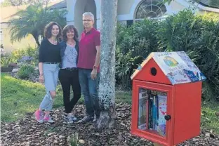  ?? STEPHEN HUDAK/STAFF ?? The homeowners associatio­n in Oviedo’s Bentley Woods neighborho­od is demanding that the Garick family, from left, Bryn, Autumn and Bob, remove the birdhouse-shaped book nook from their front yard.