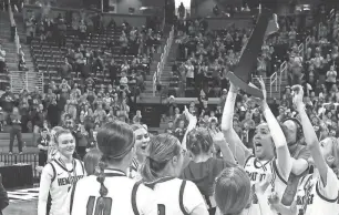  ?? ERIC SEALS/DETROIT FREE PRESS ?? Ishpeming players celebrate with their championsh­ip trophy after defeating Kingston 73-54 in the MHSAA Division 4 girls basketball finals at Breslin Center in East Lansing on Saturday.