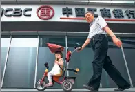  ?? PROVIDED TO CHINA DAILY ?? A man with a baby carriage walks past an outlet of Industrial and Commercial Bank of China in Beijing.