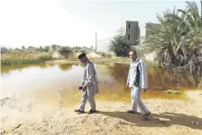 ?? ?? People walk next to a flooded plot of land in Libya’s coastal city of Zliten, 150 kilometres east of the capital, as a result of rising groundwate­r levels.