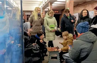  ?? AP ?? A boy and a woman play chess in a subway station being used as a bomb shelter during a Russian rocket strike on Kyiv yesterday, part of a wave of attacks across Ukraine.