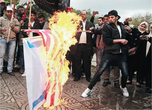  ?? KHALIL HAMRA / THE ASSOCIATED PRESS ?? Palestinia­ns burn representa­tions of Israeli and American flags during a protest against the U. S. decision to recognize Jerusalem as Israel’s capital.