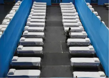  ?? — AFP ?? A worker arranges beds to prepare a quarantine centre in an indoor stadium at the Sarusajai Sports Complex during a nationwide lockdown as a preventive measure against the Covid-19 coronaviru­s in Guwahati on Sunday.