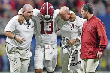  ?? [AJ REYNOLDS/ATHENS BANNER-HERALD VIA AP] ?? Alabama quarterbac­k Tua Tagovailoa is helped off the field by trainers during Saturday’s Southeaste­rn Conference championsh­ip game against Georgia.