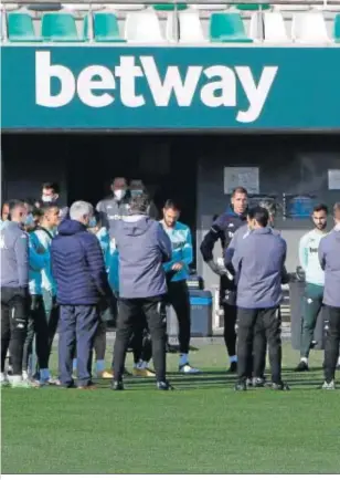  ??  ?? El cuerpo técnico dialoga con la plantilla antes del entrenamie­nto.