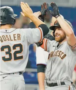  ?? MARTA LAVANDIER/AP ?? The Giants’ Donovan Walton, right, is congratula­ted by Jason Vosler and Curt Casali after hitting a grand slam in the fourth inning Sunday in Miami.