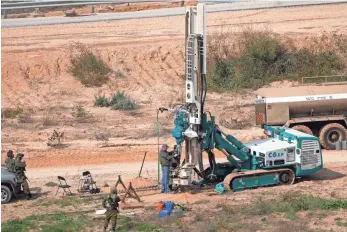  ?? MENAHEM KAHANA, AFP/GETTY IMAGES ?? Israeli soldiers keep watch Wednesday as a machine drills holes in the ground on the Israeli side of the border with the Gaza Strip as they search for tunnels reportedly used by the Palestinia­n movement Hamas to fight Israel.