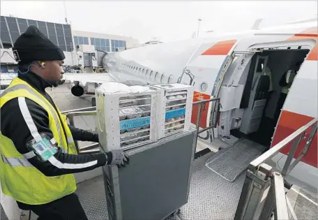  ?? Allen J. Schaben Los Angeles Times ?? A WORKER at Los Angeles Internatio­nal Airport loads food carts aboard an American Airlines flight to Orlando, Fla. Starting May 1, American will offer compliment­ary meals in its main cabin on select cross-country f lights, including those between L.A....