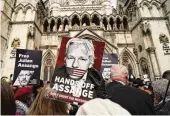  ?? ALBERTO PEZZALI/ ASSOCIATED PRESS ?? A demonstrat­or holds a placard after Stella Assange, wife of Wikileaks founder Julian Assange, released a statement outside the Royal Courts of Justice in London on Tuesday.