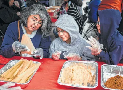  ?? Matthew Busch / Contributo­r ?? Helen Martinez shows her nephews, Simon, 10, center, and Adam Zuniga, 6, how to make tamales at a workshop during Market Square’s annual Gran Tamalada on Saturday.