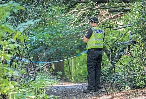  ??  ?? CORDON: A police officer stands guard at the entrance to woodland at the bottom of Broom Road in Kirkcaldy. Picture by Steve Brown.