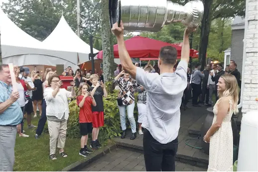  ?? - Acadie Nouvelle: Robert Lagacé ?? Alex Chiasson soulève la coupe Stanley dans les airs à son arrivée à la maison, dimanche soir. À ses côtés, sa conjointe Riley Barnes, qui est la fille de l’ex-hockeyeur Stu Barnes.