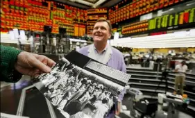  ?? Jim Young/Reuters ?? Thomas Cashman looks at some old family photos belonging to John Pietrzak, center, on the Chicago Board of Trade grain trading floor in Chicago.