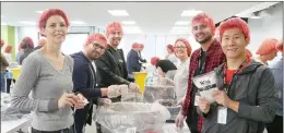  ??  ?? Employees taking advantage of their five days of volunteer time off by packaging meals with Rise Against Hunger.