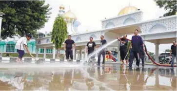  ?? AMIRUL SYAFIQ MOHD DIN / THESUN ?? ... Police Federal Reserve Unit personnel helping to clean the muddied Jalan Masjid Negri in Penang.