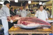  ??  ?? Employees of sushi restaurant chain Sushi-Zanmai prepare a bluefin tuna in Tokyo.