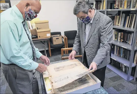  ?? Will Waldron / times union ?? Albany County Clerk Bruce Hidley, left, and Archivist Craig Carlson, right, look through 1931 times union newspaper clippings that document the shooting of Jack “Legs” diamond at the Albany County Hall of records.